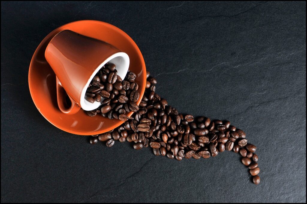 tasse à café rouge renversée avec des graines de café sortant de celle-ci
